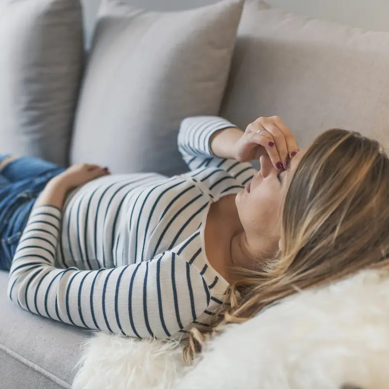 Woman lying on couch with sinus or tension headache – Chiropractor Melbourne care option