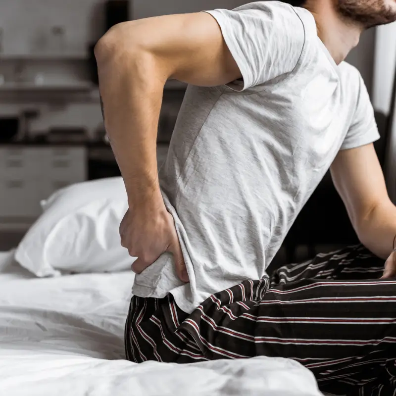 Man experiencing low back pain while getting out of bed