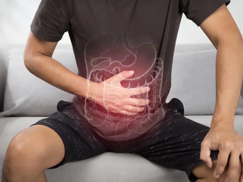 Man holding stomach indicating digestive discomfort and colon pain