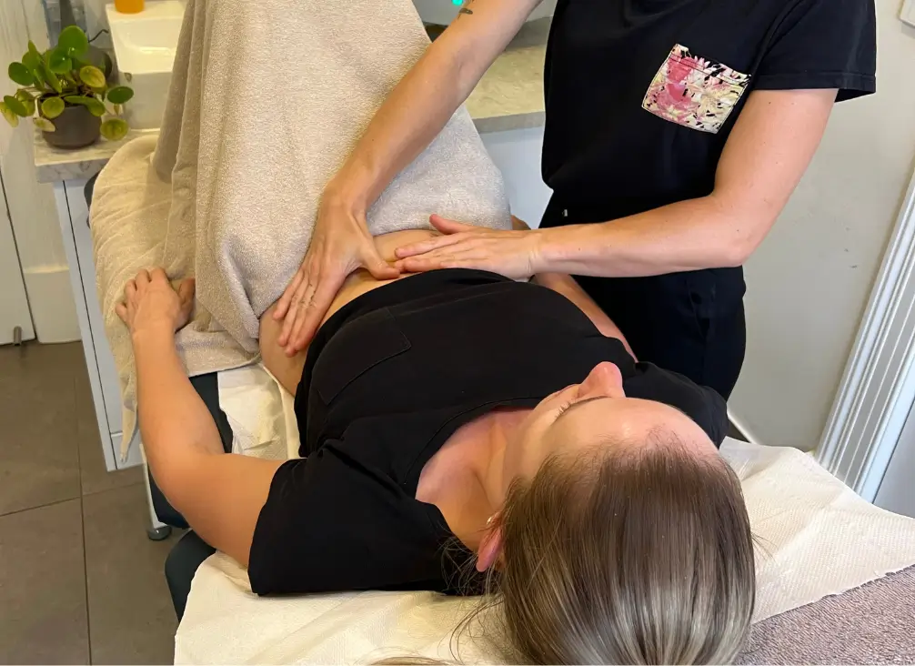 Practitioner performing abdominal massage during closed colonic hydrotherapy session
