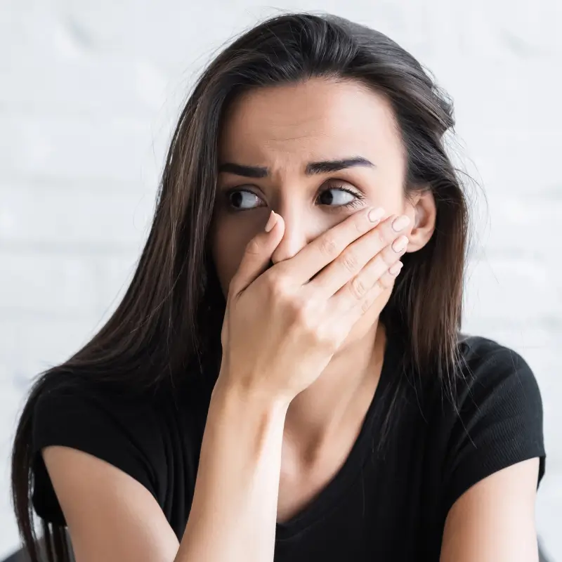 Worried woman covering her mouth after hearing misleading colonic parasite claims