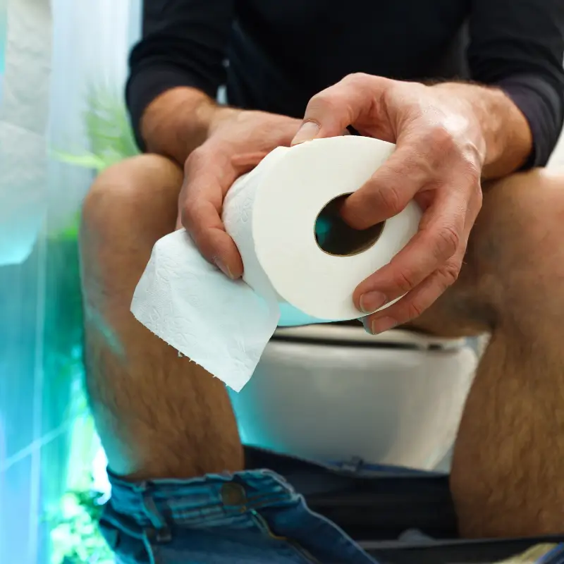 Man holding toilet paper on toilet—symbolic of bowel habits and gut health