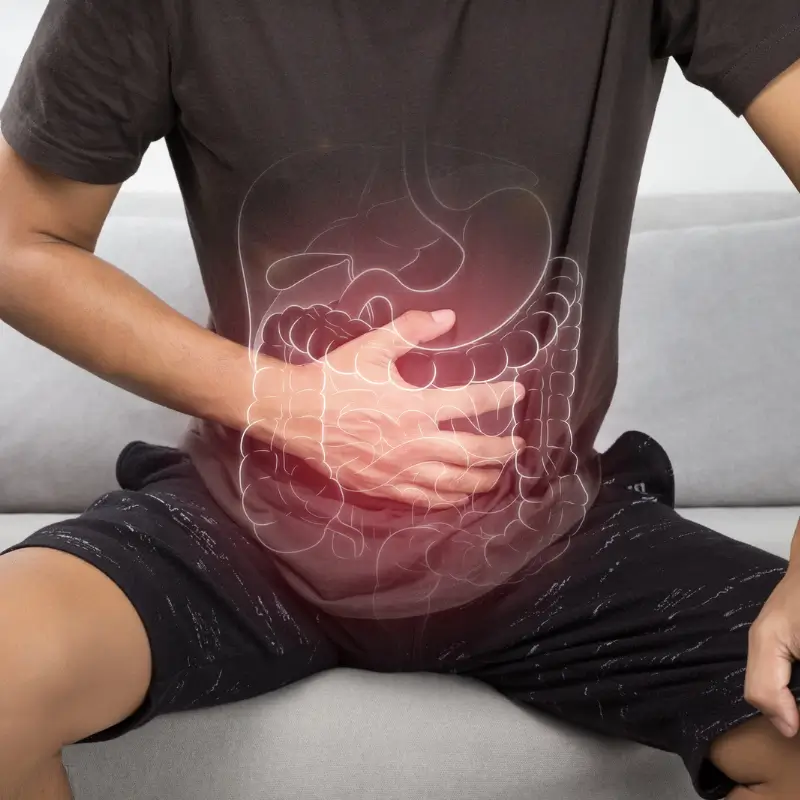 Man holding stomach indicating digestive discomfort and colon pain